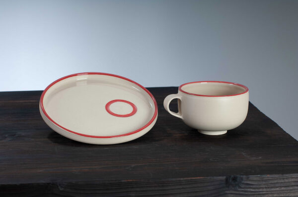 cappuccino cup and saucer with red rim side by side