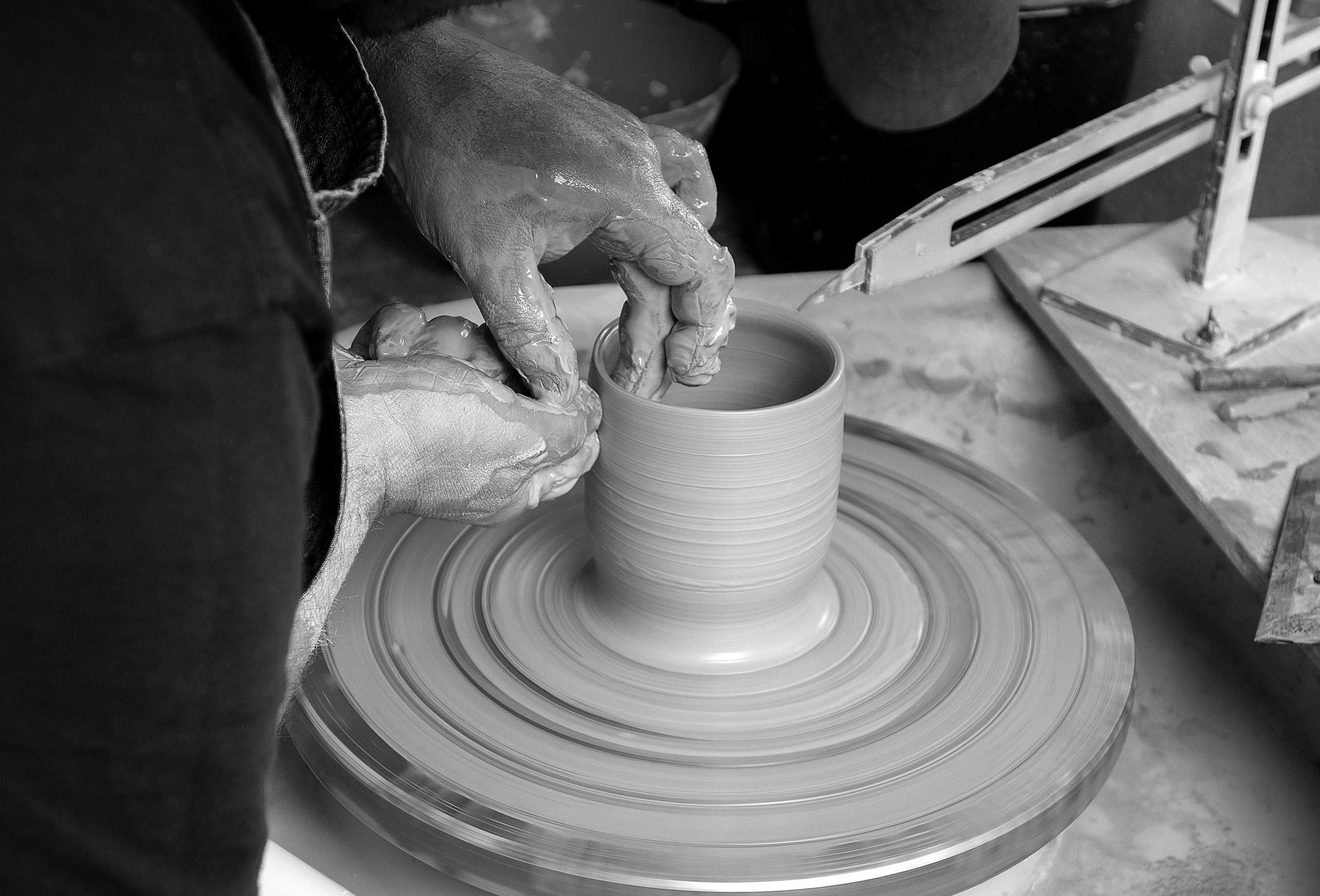 hands working on cup on potters wheel, black and white image